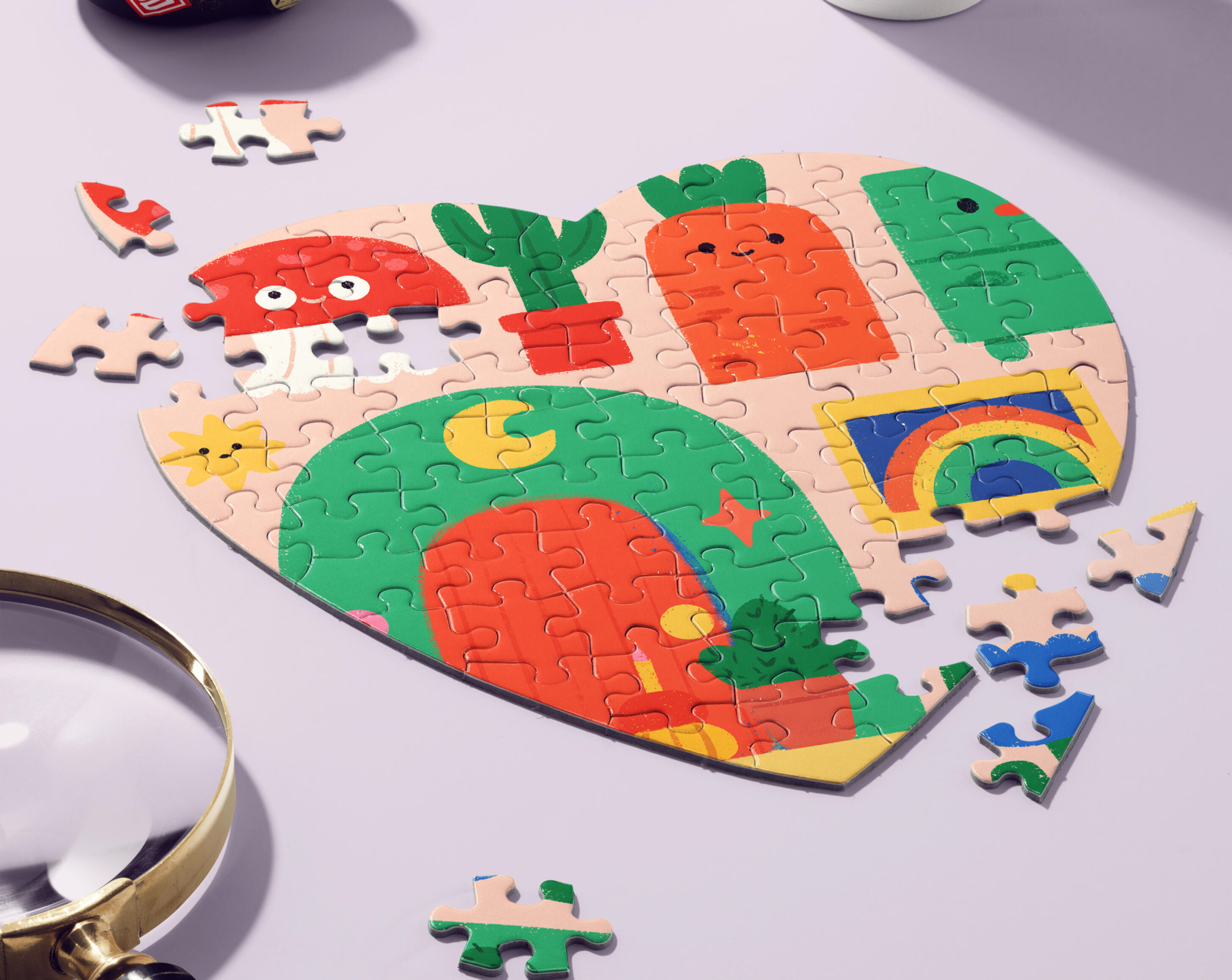 Wooden & Die-Cut Puzzles A partially assembled jigsaw puzzle on a lavender surface, printed with a colorful children’s illustration of smiling characters including a red mushroom, a carrot, a cactus, and a green archway with a crescent moon by Prudence Moth Studio.