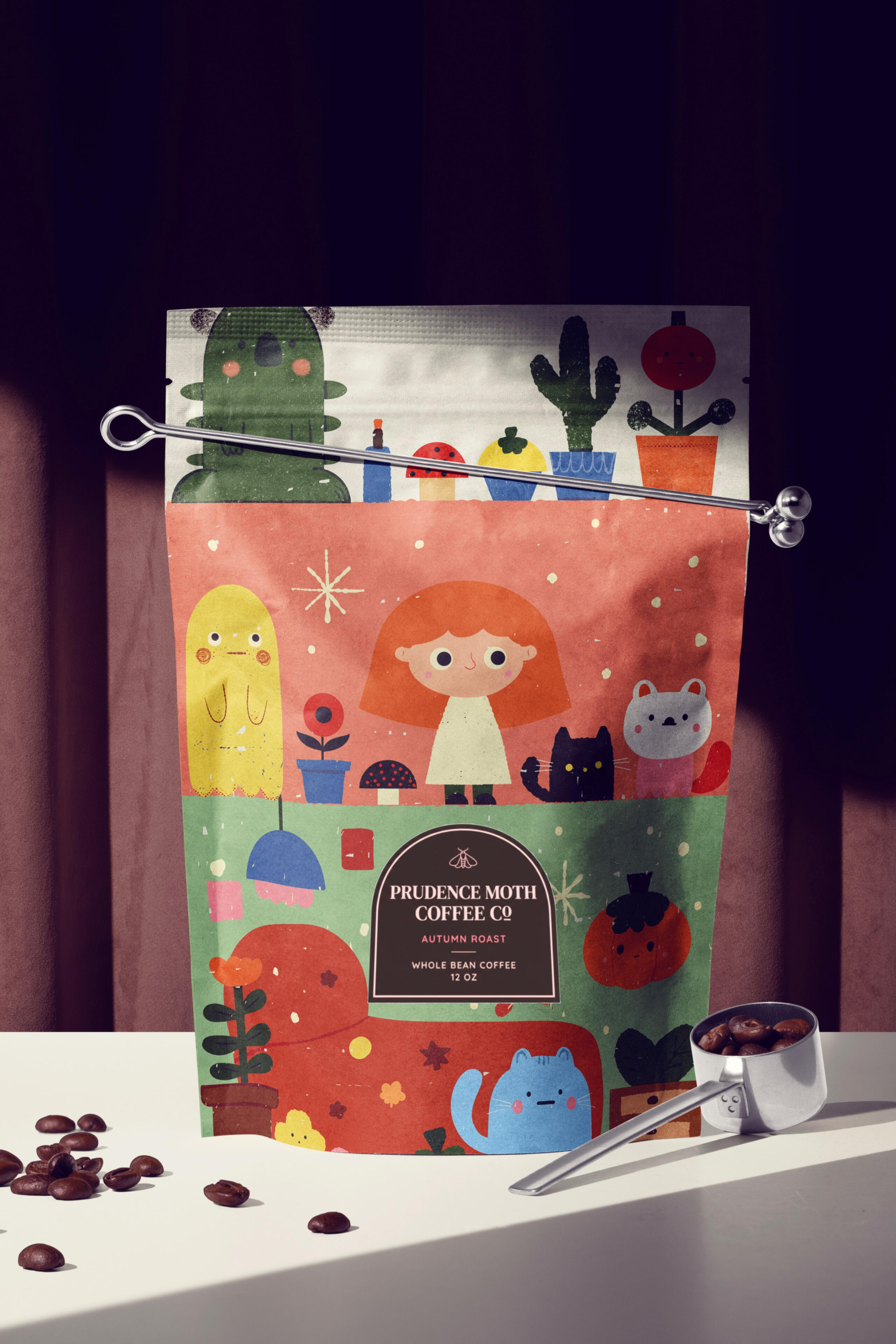 Specialty Packaging A stand-up coffee bag labeled “Prudence Moth Coffee Co, Autumn Roast” printed with a dense, colorful character illustration featuring a red-haired girl, a black cat, ghosts, mushrooms, and plants by Prudence Moth Studio.